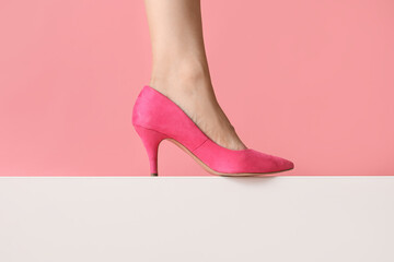 Leg of young woman in stylish pink high heel on colorful background