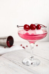 Glass of Cosmopolitan cocktail with cherries on white background