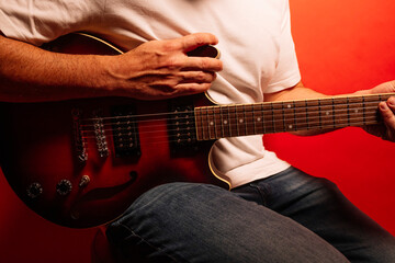 Fototapeta premium Man playing electric guitar on red background