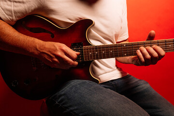Man playing electric guitar on red background