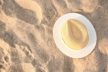 Stylish straw hat on sand