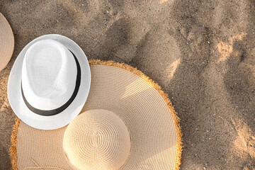 Stylish straw hats on sand