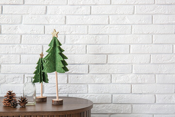Wooden cabinet with Christmas trees and pine cones near white brick wall