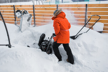 A man clear snow from backyard with snow blower. Winter season and snow blower equipment