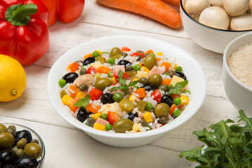 Italian rice salad in a white porcelain salad bowl on a white wooden table with ingredients. - 681764266