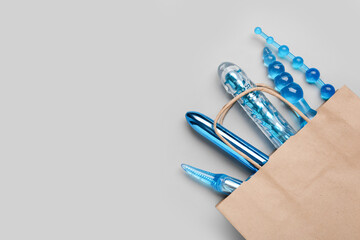 Shopping bag with sex toys on grey background