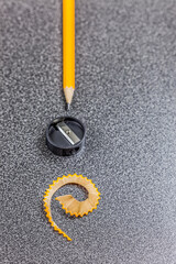 Pencil, pencil sharpener and pencil shaving on desk, close-up