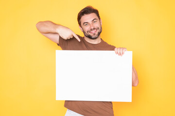 Guy with blank banner ad, isolated on studio background. Man holding empty blank poster showing...