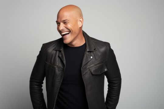 Portrait of a laughing bald man in a black leather jacket.
