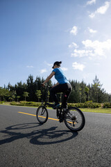 Obraz premium Riding folding bike on sunny seaside road