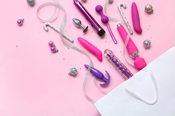 Shopping bag with sex toys and Christmas decor on pink background