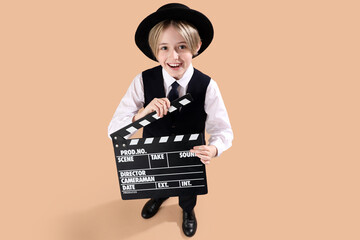 Little actor with movie clapper on beige background