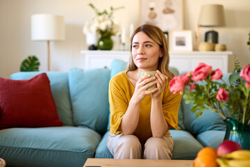 An attractive young woman relaxing at home drinking coffee in the morning