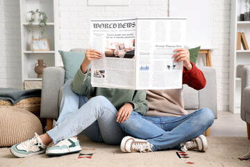Young couple reading newspaper at home