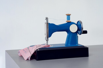 Children's small chain stitch sewing machine with manual drive is on the desktop
