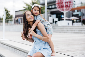 A young mother and her daughter are having fun outdoors. Mom and daughter dressed in summer dresses...