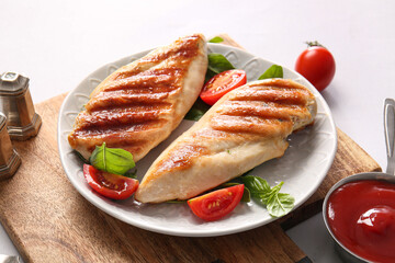 Plate of tasty grilled chicken breast with basil, tomatoes and ketchup on white background