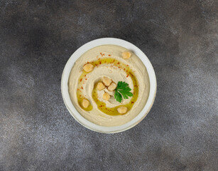 Classic hummus in a white plate on a gray background. Top view. Arabic, Turkish cuisine
