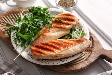 Plate with tasty grilled chicken breast and arugula on white background