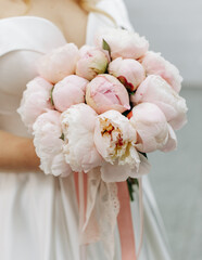 Beautiful wedding bouquet of peonies in the hands of the bride, wedding details