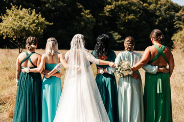 the bride in a white dress with a bouquet in her hand is holding her bridesmaids who are matched in...