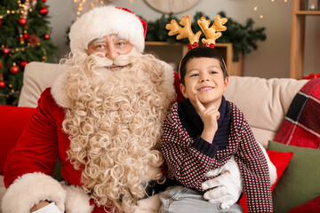Santa Claus and cute little boy in reindeer horns at home on Christmas eve
