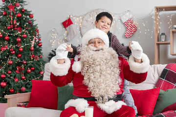 Santa Claus and cute little boy at home on Christmas eve