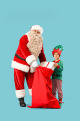 Santa Claus and cute little elf with bag full of Christmas gifts on blue background