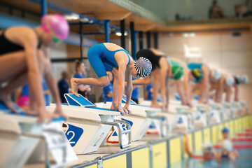 Swimmer girls start from the starting table in the pool - 681806436