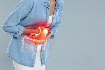 Woman suffering from stomach ache on grey background, closeup with space for text. Illustration of unhealthy gastrointestinal tract - obrazy, fototapety, plakaty