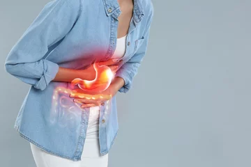 Fotobehang Woman suffering from stomach ache on grey background, closeup with space for text. Illustration of unhealthy gastrointestinal tract © New Africa