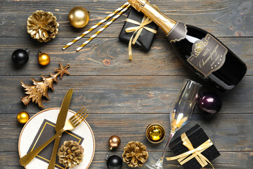 Frame made of Christmas decorations, table setting and bottle of champagne on wooden background