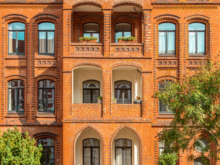 Facade of typical residential red bricks building with arched windows. Apartment house in Hannover,...