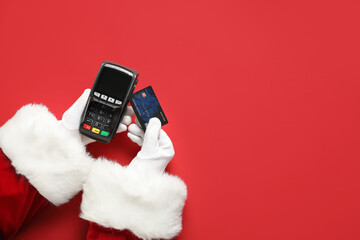 Santa Claus hands with payment terminal and credit card on red background, closeup