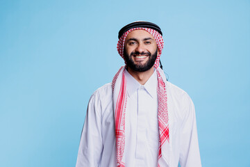 Smiling man dressed in traditional muslim clothes standing with cheerful expression studio...