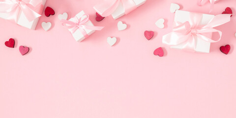 Valentine's Day background. Cute confetti hearts, gift box with bow on isolated pastel pink...