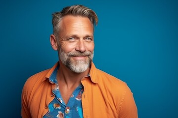 Portrait of a handsome mature man with beard and mustache on blue background