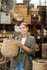 Young woman buyer in store of homemade self-made goods made of osier shoot, wicker decorative items...
