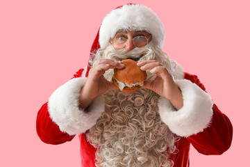 Santa Claus eating tasty burger on pink background