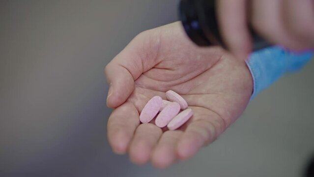 The man pours a lot of pills from a jar into his palm, close-up. Pills on hand, suicide. Male hand with medicines. Health care and medicine. Home treatment. Drug overdose.