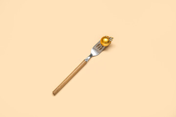 Fork with Christmas ball on beige background