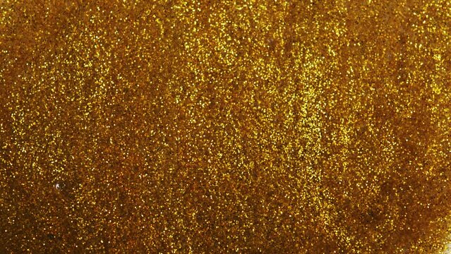 Liquid gold motion organic background. Shine glitter fluid metallic yellow color. Texture abstract acrylic. Shiny gold powder. Golden glitter particles shimmering. Beautiful metallic yellow texture.