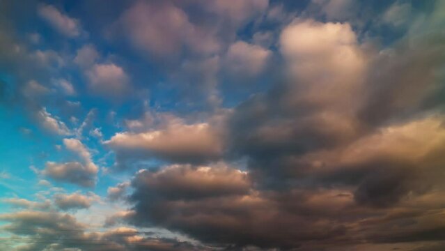 Orange clouds and gray clouds are moving across the blue sky.