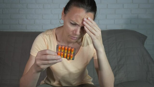 Woman think about pharmaceuticals in room. Astressed woman with head ache want to take pills in the room.