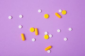 Pills and capsules on a light purple paper background. Medical treatment, pharmaceutical industry, prescription sedatives. Treatment of depression and anxiety disorders, meds, drugs
