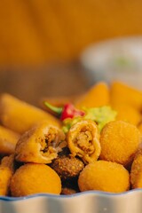 coxinha, cheese balls, mini chicken pot pies, kibbeh, risoles, pastries filled with meat or cheese, Lebanese meat pies, mini sandwiches, codfish fritters, and meat croquettes