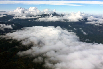Fototapeta premium View through white clouds to mountain peaks and blue sky above them