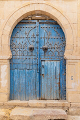 Fototapeta na wymiar A blue door in a keyhole arch, also known as a Moorish Arch.