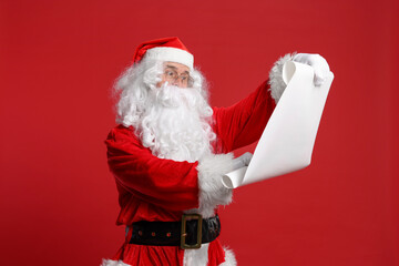 Merry Christmas. Santa Claus reading wishlist on red background