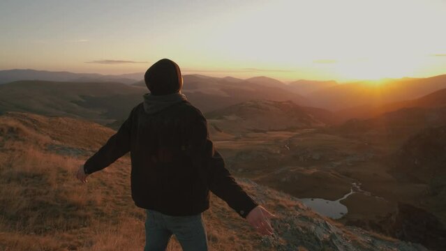 Ukrainian young man traveler walks along the most beautiful high mountain road in Romania Transalpina highway at sunset. Transalpina, Carpathian mountains in Romania at sunrise